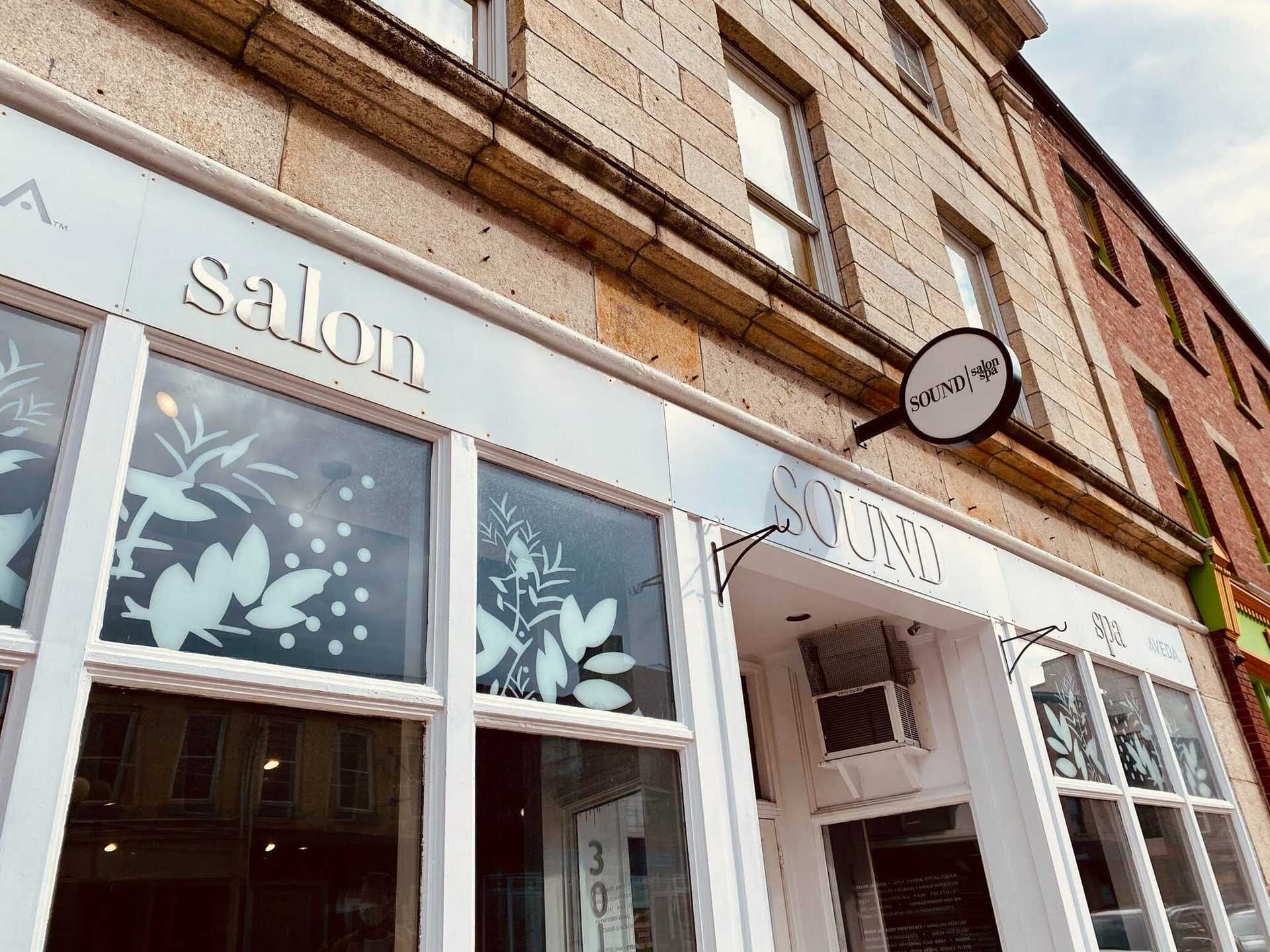 Street view of "Sound" salon and spa with floral window designs in a brick building.